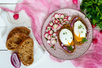 Egg poached on a piece of cereal ciabatta with a radish salad on a plate. A useful sandwich. Proper nutrition. Breakfast.