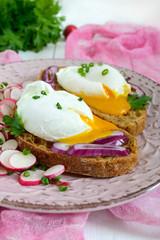 Egg poached on a piece of cereal ciabatta with a radish salad on a plate. A useful sandwich. Proper nutrition. Breakfast.