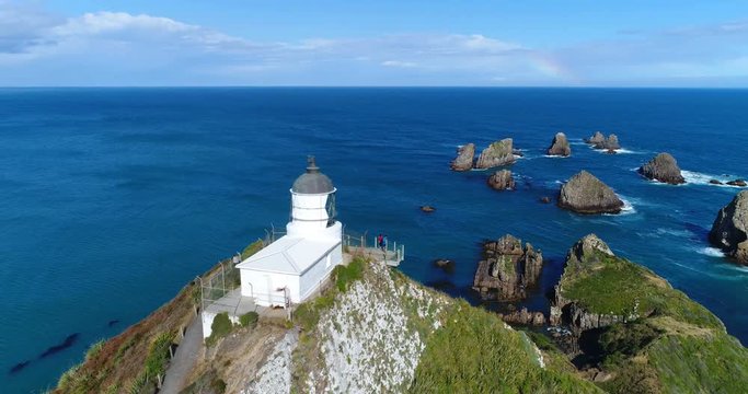 New Zealand nature landscape aerial drone footage with people sightseeing Nugget Point Lighthouse in Otago region and peninsula on South Island. Beautiful tourist destination and attraction from above