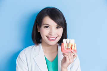 woman dentist take implant tooth