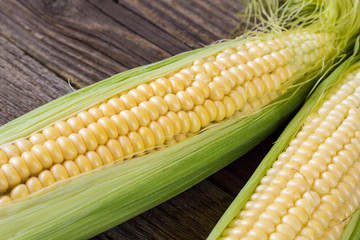 Fresh corn on cobs on rustic wooden table, closeup