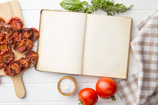 Old recipe book with tomatoes, herbs and salt.