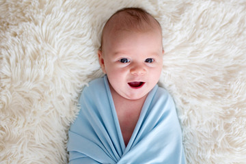 Newborn baby boy, holding a little guitarand smiling