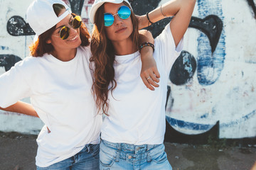 Models wearing plain tshirt and sunglasses posing over street wall - obrazy, fototapety, plakaty