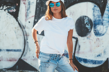 Model wearing plain tshirt and sunglasses posing over street wall
