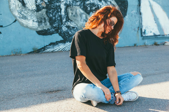 Model wearing plain tshirt and sunglasses posing over street wall
