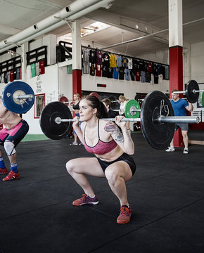 Woman Lifting Barbell With Friends In Gym