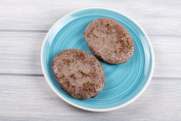 Burgers on blue plate on wooden table. Food.
