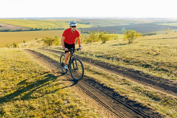 Obraz premium Bike adventure travel photo. Bike tourist rides on the country road. Sunset on background.