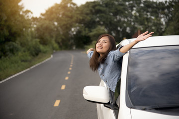 Relaxed happy woman on the road trip travel vacation leaning out car window.