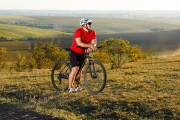 Bike adventure travel photo. Bike tourist rides on the country road. Sunset on background.