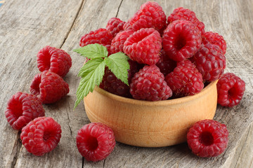ripe raspberries in wooden bowl on old wooden table background