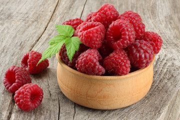 ripe raspberries in wooden bowl on old wooden table background