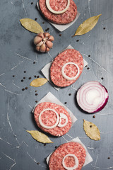 Organic fresh minced meat cutlets. Raw Ground beef meat Burger steak with ingredients on grey background