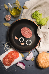 Organic fresh minced meat cutlets. Raw Ground beef meat Burger steak with ingredients in a frying pan on grey background