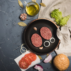 Organic fresh minced meat cutlets. Raw Ground beef meat Burger steak with ingredients in a frying pan on grey background