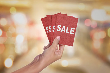Hand holding a red card with text SALE