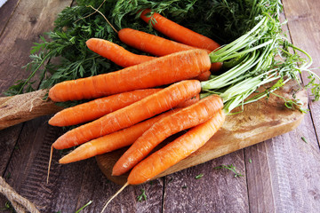 Fresh organic carrots with green leaves on wooden background. Vegetables. Healthy food