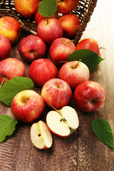 Ripe red apples with leaves on wooden background