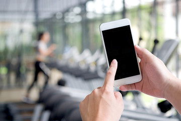 Man touch on screen smart phone with blurred fitness gym For Graphic display montage.