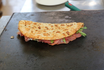 tasty piadina stuffed with ham and rocket on the hot plate to ba