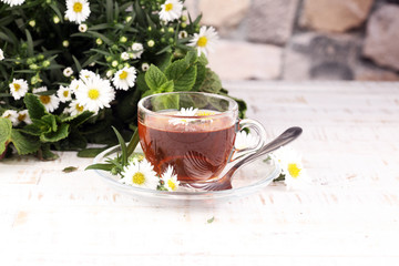 cup of tea with chamomile flowers on rustic background