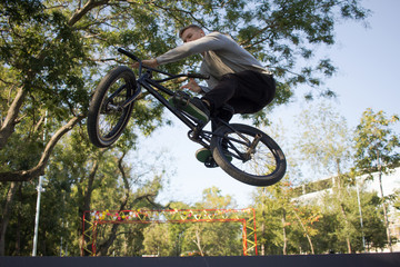 Fototapeta na wymiar BMX rider training and do tricks in street plaza, bicyxle stunt rider in cocncrete skatepark 