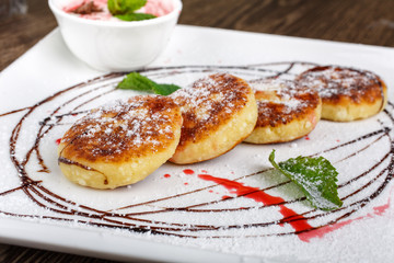 Homemade pancakes with strawberry and chocolate sauce on a wooden background.