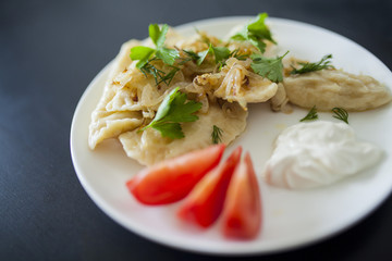 dumplings with greens and onions on a white plate