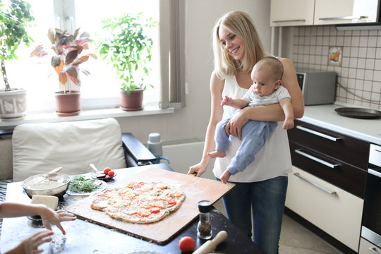 Blond Caucasian Mom With A Baby In The Kitchen