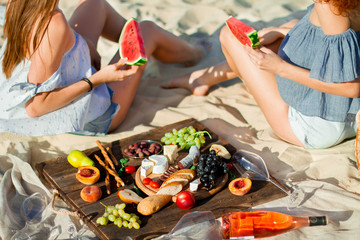 Two young female friends  on the sea shore enjoying  with watermelon.