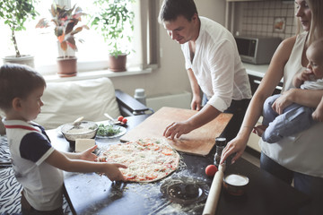 family: dad, mom, son and baby in cozy kitchen