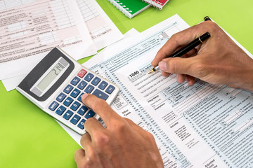 Obraz premium man filling tax form with pen, calculator