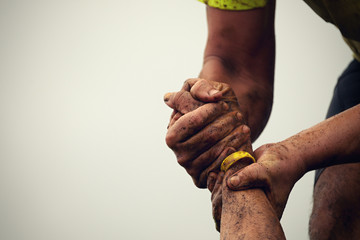 Mud race runners.Couple hold hands,help when overcoming hindrances mud - obrazy, fototapety, plakaty