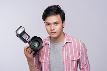 Fototapeta premium Young asian photographer holding digital camera, while working in studio