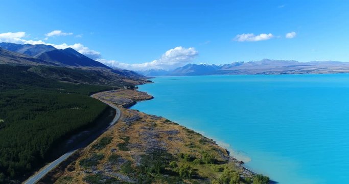 Aerial drone footage of lake Pukaki and southern alps South Island New Zealand. Road and blue lake and sky with Aoraki / Mount Cook National Park in background. New Zealand Tourist destination.