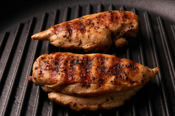Grilled chicken breast fillets on black ribbed cooking pan