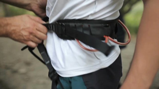 Rock climber wearing safety harness and climbing equipment, close up