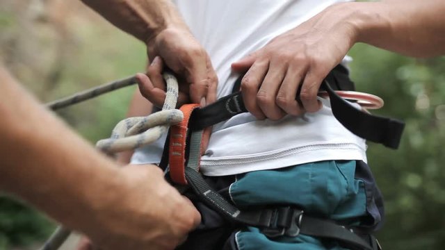 Rock climber wearing safety harness and climbing equipment, close up