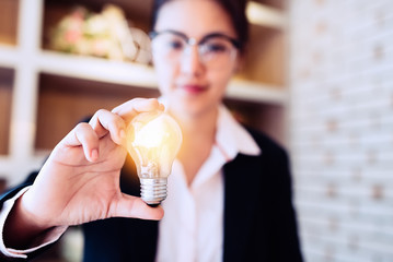 Businesswoman holding light bulb on her hands,idea concept.