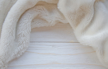 White fur on a worn white wooden background (with copy space in the center), selective focus