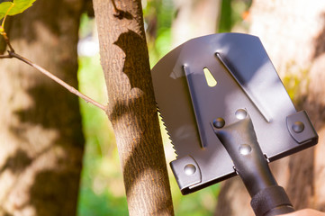 A small tourist shovel, which a man holds in his hand in the forest.