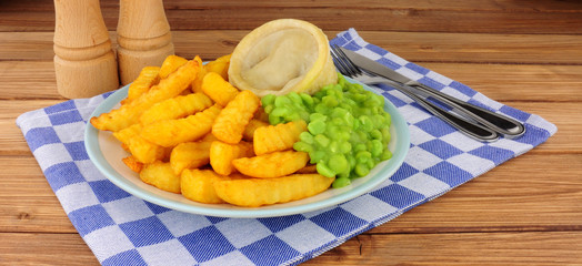 Steak and kidney pudding meal with chips and mushy peas