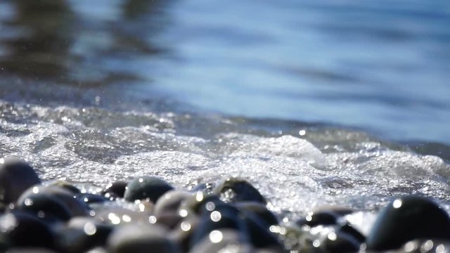 Sea beach of peebles with the foam of the waves in motion
