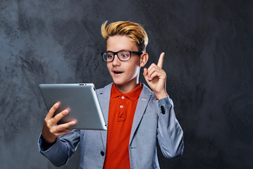 A boy in eyeglasses holds tablet PC.