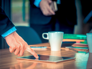 A businessman point his finger at the tablet screen on the table in the business meeting.