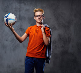 A boy plays with a soccer ball over grey background.