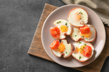 Plate with tasty eggs in ham on table