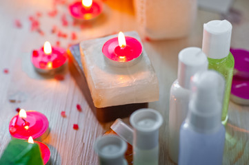 Fototapeta na wymiar SPA procedures. Multicolored pieces of soap with candles, wax and bath salt. Bathroom accessories in a bright room with white brick.