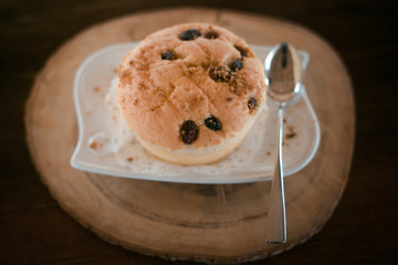 Vanilla cupcake with raisin on top, put on wooden plate.